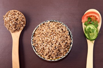 Proper nutrition. Cooked buckwheat. Fresh vegetables. Wooden spoon