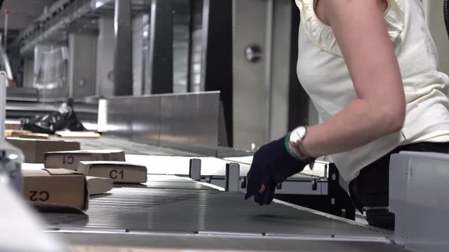 Lady correcting parcels on conveyor belt - time lapse