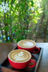 two latte art coffee in red cup