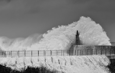 Stormy wave over old lighthouse and pier of Viavelez.