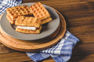 waffles with cream on plate on wooden table.