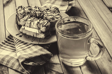 waffles with cream and chocolate on the plate and green tea on a wooden table.
