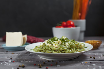 pasta green with spinach and mozzarella cheese and greens in a white plate, French mustard, colored...
