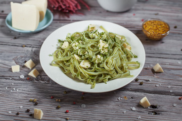 pasta green with spinach and mozzarella cheese and greens in a white plate, French mustard, colored...