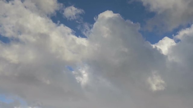 Russia, time lapse. Formation and rapid movement of white clouds of different shapes in the blue sky in late spring at sunset.