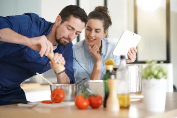 Photo sur Aluminium Cuisinier Couple en cuisine, lecture de recette sur tablette