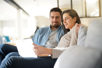 Couple relaxing in sofa and connected with digital tablet
