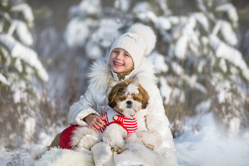 Happy smiling girl hugging her dog in a winter park
