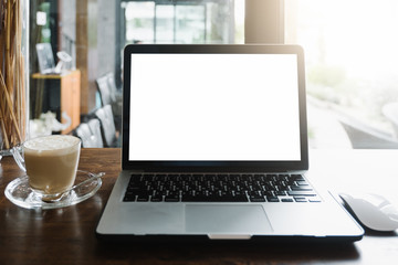 Mockup image of business woman using and typing on laptop with blank white screen and coffee cup on glass table in modern loft cafe, Soft focus on vintage wooden table.