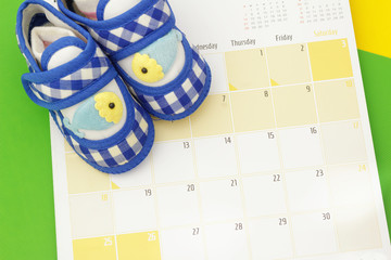 Blue baby shoes and calendar. Concept of family and pregnancy planning
