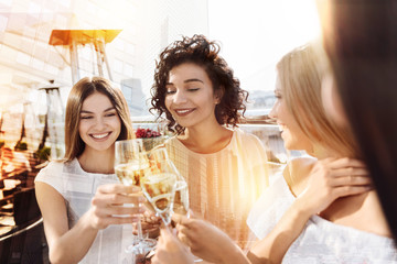 Hen party. Happy cheerful delighted women holding glasses with champagne and cheering with them while having hen party