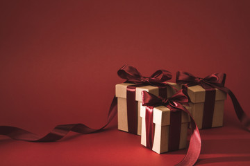 close up view of three gift boxes decorated with ribbons on red