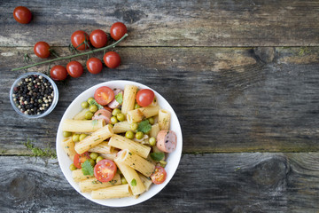 Appetizing pasta with vegetables, spices, sausages, green peas and sauce. Space for copy space.