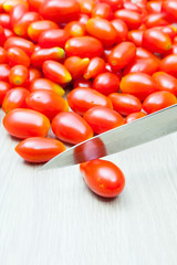 Close Up Knife Cutting Cherry Tomatoes on White Table
