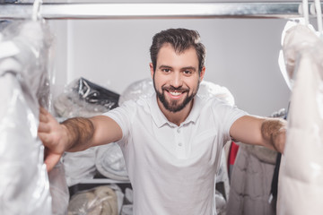 Obraz premium dry cleaning worker at warehouse with clothing packed in plastic bags