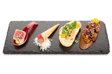 Beautiful serving of snacks with delicious fillings on an isolated dark board