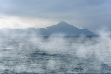 Mysterious island over ocean during foggy morning
