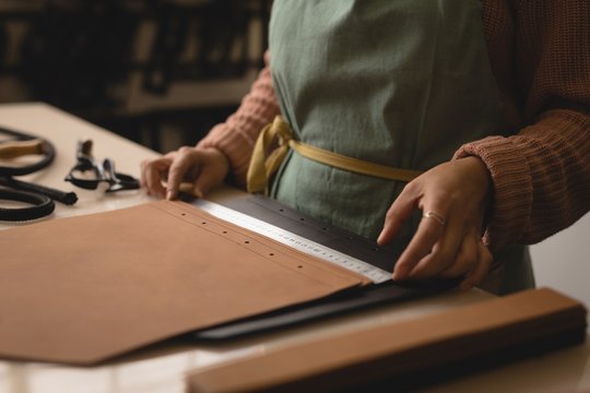 Worker measuring leather with ruler in workshop