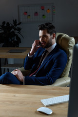 businessman talking by smartphone in dark office