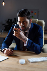 businessman drinking whiskey and looking at camera