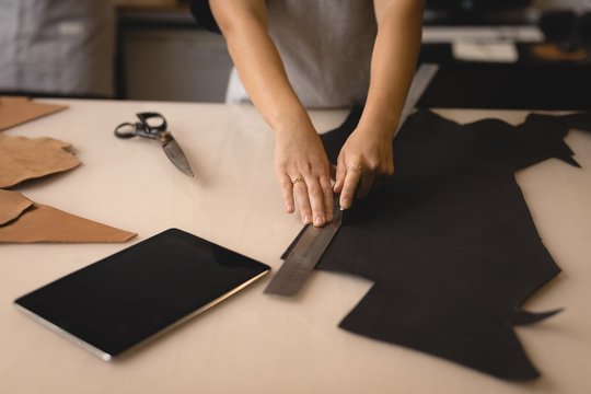 Worker measuring leather with ruler in workshop