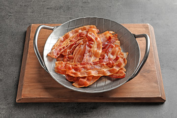 Pan with cooked bacon rashers on table