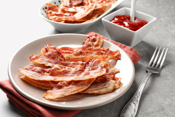 Plate with cooked bacon rashers on table