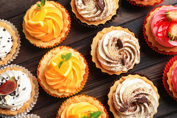 Tasty colorful cakes on wooden background, top view
