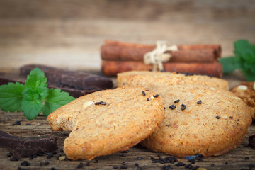 Oat cookies with chocolate and cinnamon on wooden board, close up.
