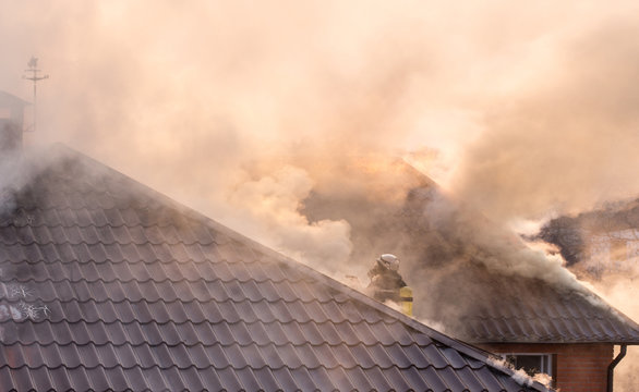 Firemen fighting a raging fire with huge flames of burning timber.