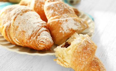 Plate with tasty croissants on table, closeup