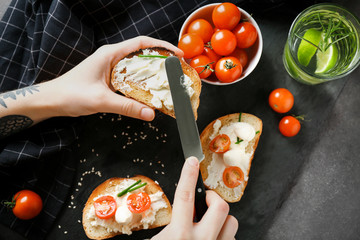 Woman spreading cream cheese on toast over table, top view