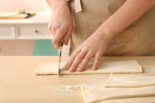 Woman cutting puff pastry on table