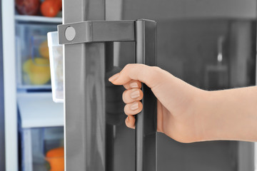 Woman opening refrigerator door, closeup