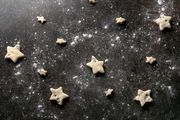 Fototapeta premium Raw cookies in shape of stars on dark background
