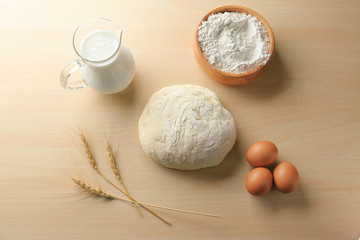 Fresh raw dough with ingredients on wooden table