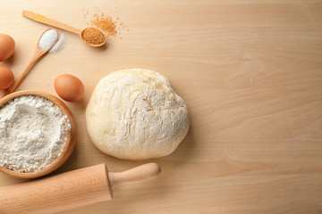 Fresh raw dough with ingredients on wooden table