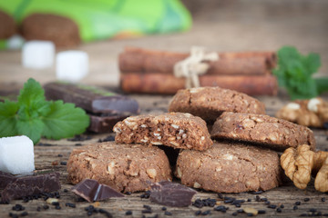 Pile of cookies with chocolate and nuts on rustic wooden table