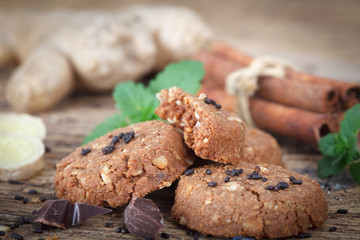 Ginger cookies with chocolate and nuts on rustic wooden table