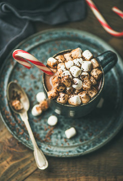 Winter warming sweet drink hot chocolate with marshmallows and cocoa in mug with Christmas holiday candy cane, selective focus