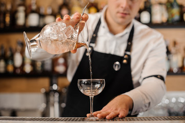 Barman adding vodka into a cocktail glass