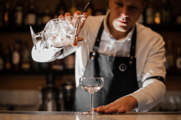 Barman adding vodka into a cocktail glass in the dark light