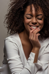 Young smiling african american woman in white shirt isolated on grey background