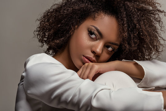Young sensual african american woman in white shirt looking away isolated on grey background