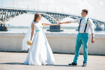 the bride and groom are photographed on the background of the bridge