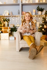 Photo of girl sitting in chair on background of Christmas decorations