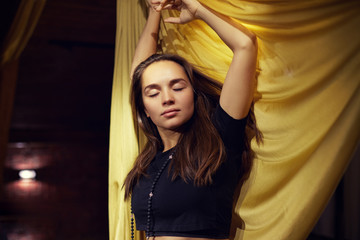 Obraz premium Calm atmosphere and meditating concept. Restful brunette female being at yoga studio, feels relaxed, dancing with mudras, tries to concentrate or focused, closes eyes, enjoys silence, finds balance.