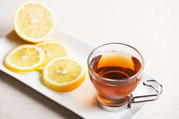 Tea cup with lemon on white plate. Infusion.