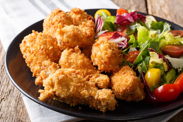 deep-fried chicken wings in breadcrumbs and fresh salad close-up on a plate. horizontal © FomaA