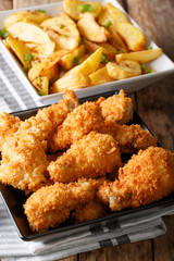 Fast food: fried chicken wings in breadcrumbs and potato close-up. vertical